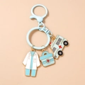 Detailed close-up of nurse uniform and ambulance medical charms on a gold keychain - Blue