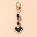 Macro detail of pixel heart keychain with gold clasp and acrylic beads in retro style - Black