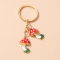 Dettaglio dei ciondoli a fungo rosso a pois con portachiavi dorato e dettagli foglia - Fungo con Foglia Verde