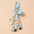 Detail eines Schlüsselanhängers mit Krankenwagen, Thermometer und blauen Perlen - Blau