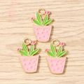 Detailed view of three pink cactus enamel charms with golden edges on wood texture - Pink