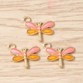 Detailed macro of gold plated dragonfly charms with pink and orange enamel for DIY jewelry - Yellow-Pink