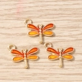 Detail of three gold-plated dragonfly pendants with orange enamel for DIY jewelry making - Orange