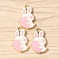 Detailed macro view of three white and pink enamel cartoon rabbit charms with golden edges - Rose Red