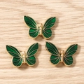 Macro shot of dark green enamel butterfly charms with gold metal filigree details - Green