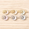 Détail de pendentifs étoile et lune en or et argent avec touches rose, blanc et bleu - Multicolore