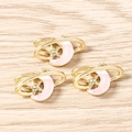 Detailed close-up of three pink enamel moon and gold star pendants on a wood surface - Gold Pink