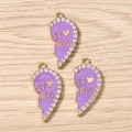 Detailed close-up of gold-plated half-heart pendants with purple enamel and white zircons - Purple