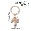 Detail view of colorful enamel milk tea pendants with red hearts on a golden keychain - White Blue Milk Tea