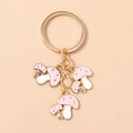 Detalle de tres colgantes de setas en esmalte rosa en un llavero dorado con lunares - Rosa