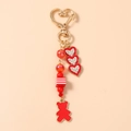 Detail of red bear keychain featuring heart-shaped gold clasp and beaded charms - Red