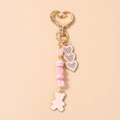 Close-up of pink beaded keychain with a gold heart clasp and enamel bear charm - Pink