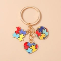 Dettaglio portachiavi autismo con ciondoli puzzle e cuore su anello in metallo oro - Puzzle a Cuore Blu Giallo Rosso
