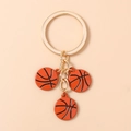 Détail d'un porte-clés mode avec trois pendentifs de basket-ball texturés sur un anneau doré - Calicot