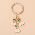 Detail shot of three pink enamel cherry pendants with green leaves on a gold keychain - Pink