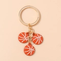 Detail van drie mini oranje basketbalhangers met gouden sleutelhangers en kettingen - Bruin en Wit