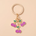 Detailed macro view of cherry keychain with burgundy enamel fruits and golden ring - Purple