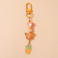 Detail van de oranje kralen sleutelhanger met vlinder en cactus bedeltjes op crème - Oranje