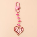 Detail view of heart-shaped keychain with pink stone beads and enamel charm pendant - Red
