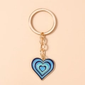 Detail van gouden hartvormige sleutelhanger met blauw emaille verloop op roze - Blauw