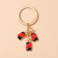 Detail von drei Mini-Cola-Dosenanhängern in Rot und Schwarz an goldenem Schlüsselring - Schwarz
