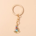 Close-up of golden sailboat keychain with vibrant multicolor enamel sails and metal ring - Colorful
