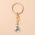 Detailopname van een gouden zeilboot sleutelhanger met blauw en wit emaille - Blauw