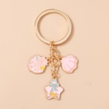 Detalle de los colgantes de estrella de mar y concha rosa en un llavero dorado - Rosa Concha Estrella de Mar