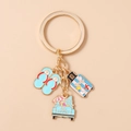 Detailed shot of gold-tone summer keychain with flip-flop, suitcase, and surf car charms - Suitcase Car Slippers