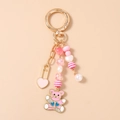 Detailed view of pink enamel bear keychain with golden metal heart charms and beads - Pink