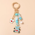 Detail view of blue beaded keychain with bear pendant, mini t-shirt and large white pearl - Blue