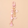 Detail of pink resin beads, kiss me charm and heart watering can on a golden keychain - Watering Can Heart
