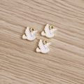 Detailed close-up of three white enamel dove pendants with gold metal frames on wood - White