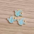 Detailed view of three sky blue and gold swallow bird charms on a light wood background - Blue