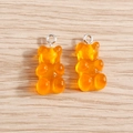 Detail view of two orange resin gummy bear charms with silver rings on wood surface - 10 Pieces Pack / Orange