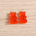 Close-up of translucent orange resin gummy bear charms with silver metal rings on wood - 10 Pieces Pack / Red