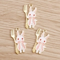 Detailed view of white enamel bunny pendants with gold forks on a wood background - Fork Style / 10 Pieces Pack / Pink