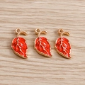 Detailed close-up of three red enamel maple leaf charms with golden metal edges - Red