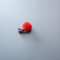Red pom-pom hair clip for girls with a fabric wrapped duckbill clip on blue background - Red