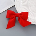 Red ribbon bow hair clip for New Year featuring a soft texture on a ceramic plate - Handmade Bow Hair Clip