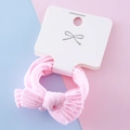 Rosa Cord-Haargummi mit Schleife auf weißer Karte vor pastellfarbenem Hintergrund - Rosa