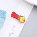 Detalle de la pinza para el pelo navideña con campanas amarillas y lazo rojo sobre tarjeta - Campanas de Navidad Doradas