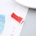 Primer plano de una pinza para el pelo con gorro de Navidad rojo y pompón blanco - Pinza para el Cabello de Sombrero