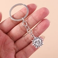 Retro-Sonnenschlüsselanhänger in Antik-Silber-Optik in der Hand vor rosa Hintergrund - Sonne Und Mond Stil