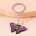 Detail eines lila Schmetterling-Schlüsselanhängers auf einem rosa gestuften Ständer - Lila