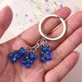 Detailed view of three blue resin glitter bears on a silver keychain held in hand - Dark Blue