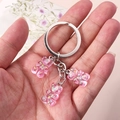 Detailed shot of pink resin gummy bear keychains with glitter held in a hand - Glitter