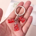 Detail of red glitter resin gummy bear charms on a silver metal keychain held in hand - Glitter Bear Style / Red