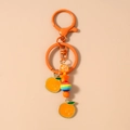 Detailed macro view of orange starfish bell keychain with colorful beads and charms - Orange