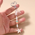 Dettaglio del portachiavi a stella con perle floreali e cristalli sulla stella marina - Bianco